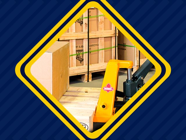 Paleteira manual amarela transportando um palete com caixa